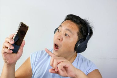 Akıllı telefonlu Asyalı adam müzik dinliyor.