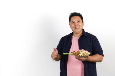 Bir tabak lezzetli Endonezya usulü kızarmış erişteli Asyalı adam başparmağını kaldırıyor.