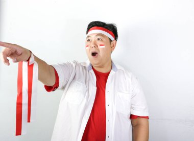 Kırmızı tişört giyen mutlu Asyalı adam, fotokopi alanını işaret ediyor.