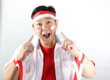 Asyalı adam kırmızı tişört ve beyaz bayrak giyiyor ve zafer işareti gösteriyor.