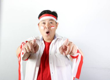 Asyalı bir adam kameraya işaret ederek zafer işareti yapıyor.