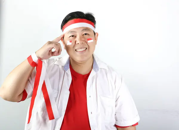 Kırmızı tişörtlü, beyaz tişörtlü, elinde futbol topu olan Asyalı bir adamın portresi ve zaferini beyaz arka planda kutluyor.