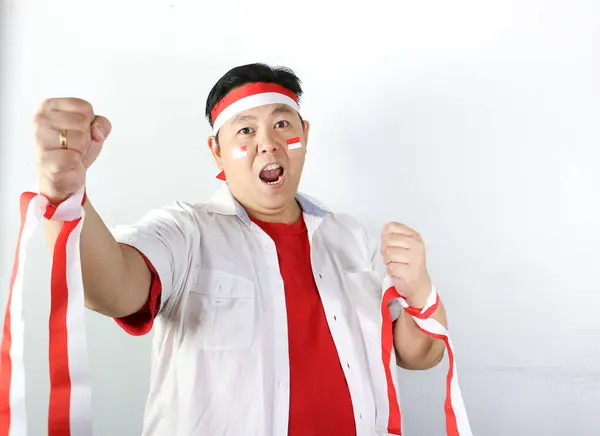 Zaferi kutlayan Asyalı genç bir adamın portresi ve beyaz arka planda izole edilmiş yüzünde mutlu bir ifadeyle kameraya bakmak..