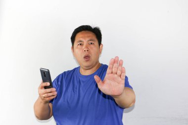 Akıllı telefon kullanan Asyalı bir gencin portresi hayır diyor, reddedilme hareketi.