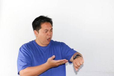 Kızgın Asyalı adam işe geç kaldığı için saatini arıyor.