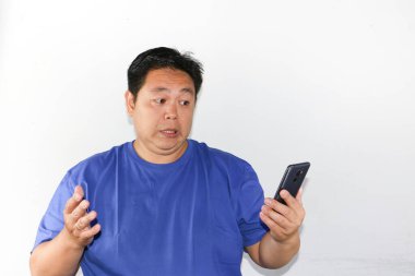 Asyalı adam cep telefonuna bakarken şok oldu ve şaşırdı.