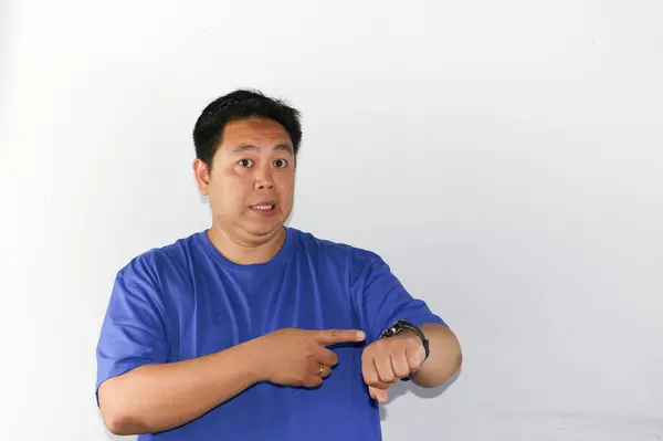 Asyalı bir adamın portresi, beyaz arka planda el izolasyonuyla saatini gösteriyor.