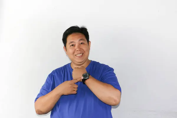 Mutlu bir Asyalı erkek parmağını kol saatine doğrultuyor.