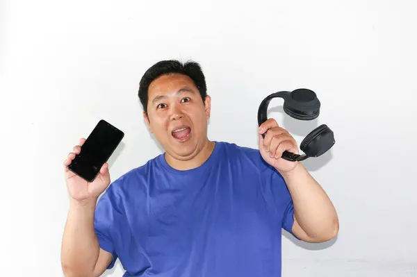 Kulaklıklı genç Asyalı bir adam ve bir fincan kahve.