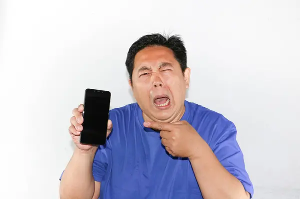 Adam üzgün ve ağlayan yüz ifadesiyle akıllı bir telefon tutuyordu.