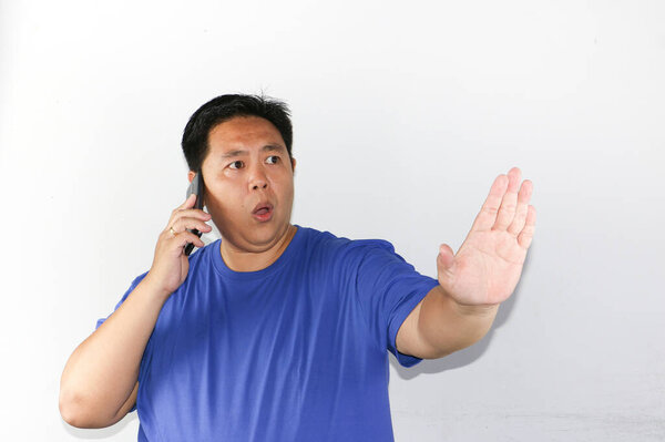 Отказ жест азиатский человек с умной повседневной рубашкой стоя на белом фоне держа мобильный телефон