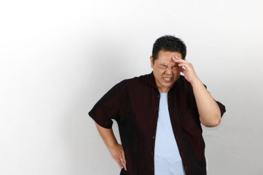 Asyalı bir adam başını kötü bir baş ağrısından tutuyor.