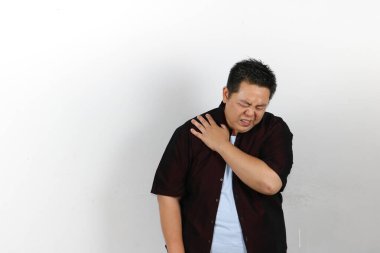 Omuz ağrısı çeken genç Asyalı adam beyaz arka planda izole edilmiş..