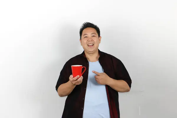 Elinde kırmızı kahve fincanı tutan neşeli genç adam.