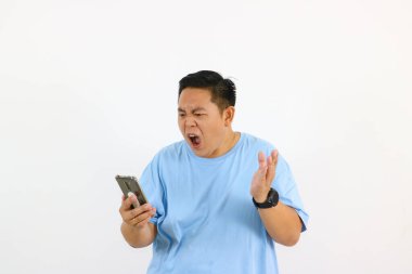 Mavi tişörtlü adam, telefonuna öfkeyle tepki veriyor.