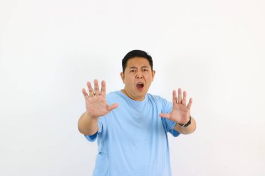 Şaşırmış bir adam beyaz bir arka planın önünde el kol hareketi yapıyor.