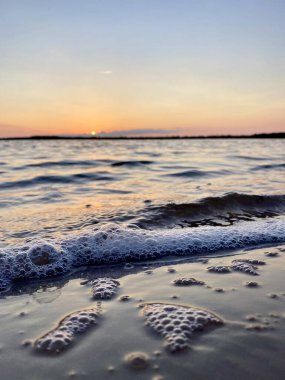 Gün batımında ya da gündoğumunda sakin bir denizin dalgaları ve kabarcıkları. Yüksek kalite fotoğraf
