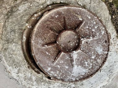 Yıpranmış beton yüzeydeki paslı yuvarlak metal kapağı kapatın.