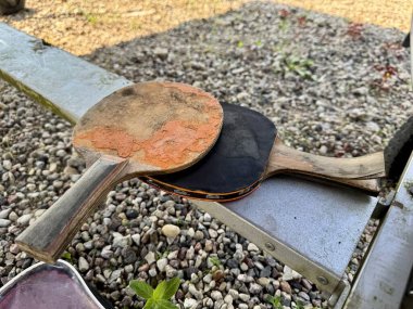 Çakıl taşlı arka planı olan eski moda masa tenisi raketleri.