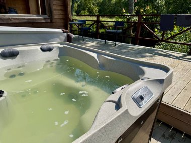 İhmal edilmiş açık hava jakuzisi alg ve kirlilikle kaplı bulanık yeşil suyla dolu.. 