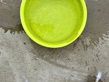 Islak beton zemine döşenmiş parlak plastik kase.