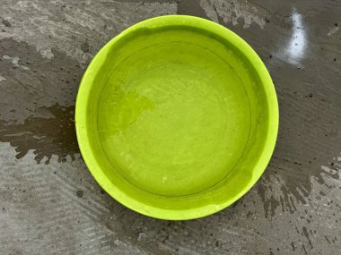 Islak beton zemine döşenmiş parlak plastik kase.