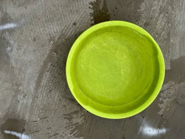 Islak beton zemine döşenmiş parlak plastik kase.