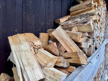 Doğranmış odun yığını depolama ve kış ısıtması için koyu ahşap duvarın yanına yerleştirilmiş.