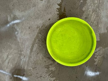 Islak beton zemine döşenmiş parlak plastik kase.
