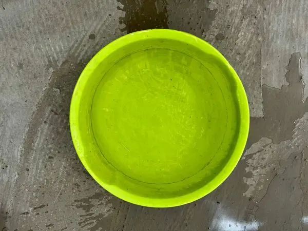 Islak beton zemine döşenmiş parlak plastik kase.