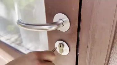 İnsan eli kolu çeviriyor ve ön kapıyı içeride açıyor.