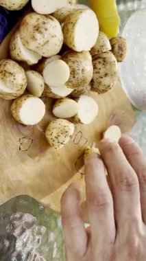 Pişirme hazırlıkları için mutfak masasında taze patatesleri dilimlerken elinizi kapayın.