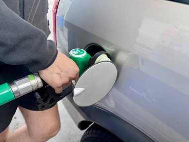 Hand refueling car with green eco friendly fuel nozzle at gas station