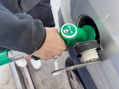 Hand refueling car with green eco friendly fuel nozzle at gas station