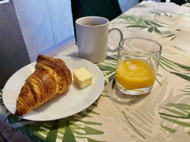 Sabah kahvaltısı taze sıkılmış meyve suyu, tereyağlı kruvasan ve siyah çay.