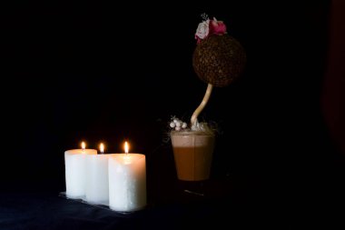 Üç yanan mum, Paskalya arifesinde karanlıkta kahve çekirdeğinden yapılmış yapay bir çiçek.