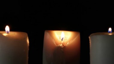 Paskalya bayramının arifesinde karanlıkta meşe tezgahında yanan üç mum.