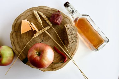 Elmalarla, diğer ürünlerle meşe tezgahında buğday kulaklarıyla ve çam fıstığının üzerinde ev yapımı sert bir tentürle dolu bir şişe