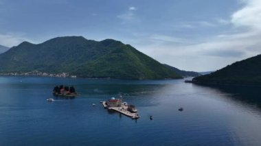 Kotor Körfezi 'ndeki Kayalıklardaki Meryem Kilisesi' nin arka planındaki dağlara karşı. Karadağ 4K stok videosu.