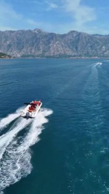 Karadağ 'ın Kotor Körfezi' ndeki yemyeşil dağlar ve berrak sularla çevrili teknelerin manzaralı görüntüleri.