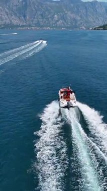 Kotor Bay Montenegro 'nun turkuaz sularda ve dramatik dağ manzaralarında hareket eden tekneleriyle çekilmiş güzel insansız hava aracı görüntüleri.