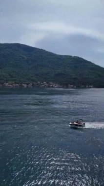 Karadağ Kotor Körfezi 'nin el değmemiş sularında yüzen küçük teknelerinin muhteşem insansız hava aracı görüntüleri. Dikey video.
