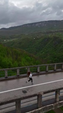 Tara Nehri üzerinde koşan kadının robot görüntüsü. Yüksek kaliteli 4K görüntü. Dikey video. Dzhurdzhevich Köprüsü.