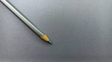  Gri arka planda kısa, yıpranmış gümüş bir kalem yaratıcılığı, kullanımı ve inadı simgeliyor..