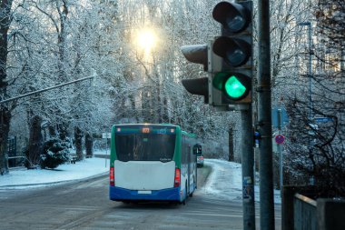 Almanya, Bavyera 'da trafik ışıkları ve kış ağaçlarıyla dolu, karlı bir caddeden geçen Yeşil ve Mavi Kamu Otobüsü. Yüksek kalite fotoğraf