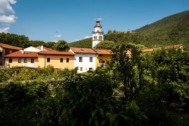 Vipava 'nın Kale Manzaralı Büyüleyici Kasabası: Batı Slovenya' da Açık Mavi Gökyüzü Altında Uzak Kale Harabeleri Olan Renkli Tarihi Evler ve Kilise Kulesi