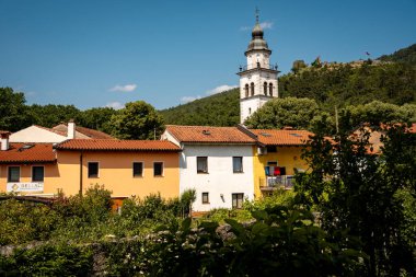Vipava 'nın Kale Manzaralı Büyüleyici Kasabası: Batı Slovenya' da Açık Mavi Gökyüzü Altında Uzak Kale Harabeleri Olan Renkli Tarihi Evler ve Kilise Kulesi