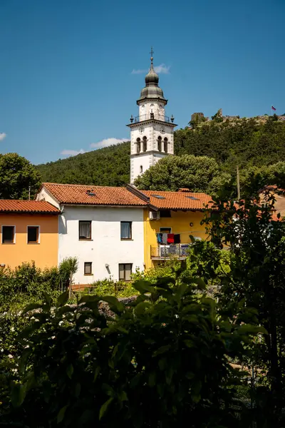 Vipava 'nın Kale Manzaralı Büyüleyici Kasabası: Batı Slovenya' da Açık Mavi Gökyüzü Altında Uzak Kale Harabeleri Olan Renkli Tarihi Evler ve Kilise Kulesi