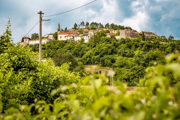 Slovenya 'nın Manzaralı Tepe Kenti Stanjel: Karst Bölgesi' nde Geleneksel Taş Evler ve Çiçek Yeşiller Altında Yükselen Tarihi Kilise Kulesi. Yüksek kalite fotoğraf