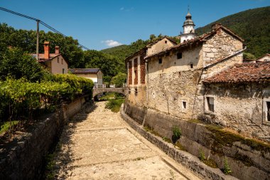 Vipava 'nın Kale Manzaralı Büyüleyici Kasabası: Batı Slovenya' da Açık Mavi Gökyüzü Altında Uzak Kale Harabeleri Olan Renkli Tarihi Evler ve Kilise Kulesi